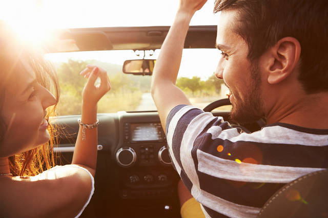 Young Couple Driving In Open Top Car