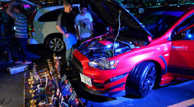 two men looking at red car