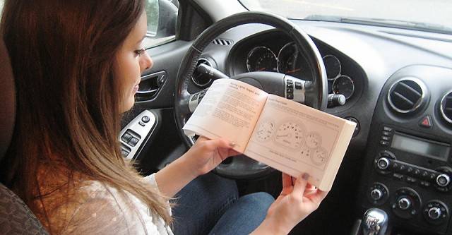 Girl in the car reading her car manual