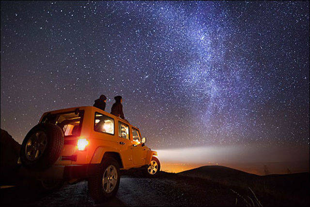 Couple star gazing on a yellow car