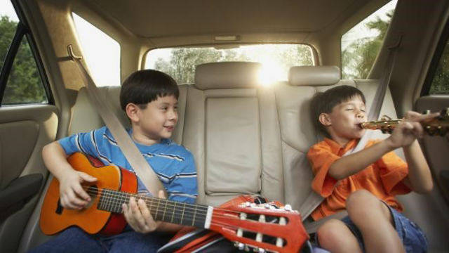 Two children playing musical instruments in a car