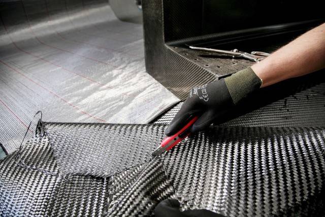 A sample of carbon fiber sheet being cut by a worker.