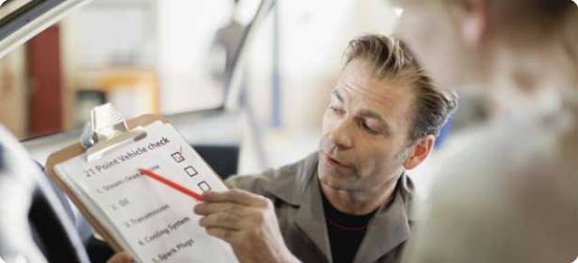 Man showing a buyer a list of what they're inspecting in a used car